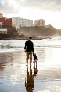 A touching family moment of a father and child walking hand in hand on a sunset beach.