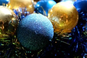 A close-up shot of glittery blue and gold Christmas balls and tinsel.