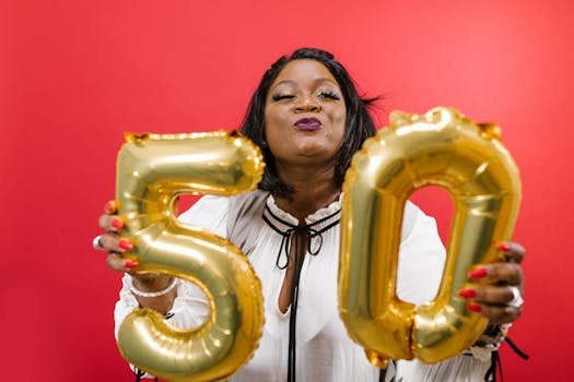 Joyful woman holding golden 50 balloons against a vibrant red background.